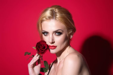 Güzel stüdyo portresi. Kırmızı gül çiçekli güzel bir model, kırmızı stüdyo arka planında izole edilmiş. Mükemmel makyajlı hoş bir genç kız.