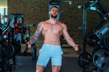 Spor salonunda egzersiz yapan güçlü bir genç adam. Spor kulübünde spor erkek antrenmanı. Genç adamın fitness antrenmanı var. Erkek sporcu egzersiz, spor ve antrenman yapar. İnsanlar spor ve sağlıklı yaşam tarzları