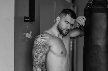 Spor salonunda güçlü bir boksör. Sıkı boks. Spor kulübünde kum torbasıyla spor erkek antrenmanı. Genç adamın fitness antrenmanı var. Erkek sporcu spor yapar.