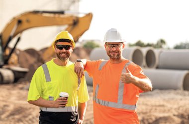 İnşaat işçileri kask takarak çok çalışıyor. Sert şapkalı iki işçi bina inşa ederken güvenliği sağlamaktan sorumludur. İnşaatçılar kişisel koruyucu ekipman