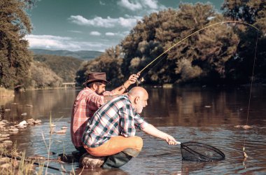 Balıkçıların arkadaşları ve ganimet alabalıkları. Baba oğul balık tutuyor. Nesiller boyu nehirde balık tutan adamlar