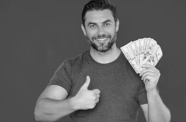 stock image Handsome man holding money isolated over grey studio. Money in dollar banknotes. Pile of cash, finance, investment and money saving