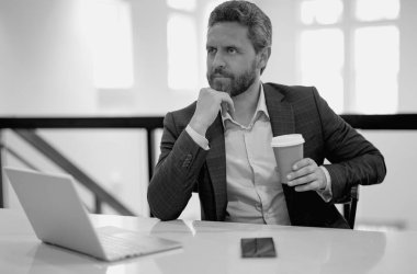 Ofiste çalışan ciddi bir iş adamı. Ofiste dizüstü bilgisayar kullanan sıradan takım elbiseli yakışıklı bir iş adamı. Resmi takım elbiseli bir ofis çalışanı. Ofis yöneticisi CEO iş adamı dizüstü bilgisayar kullanıyor