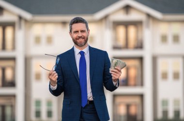 Emlak yatırımı. İyi ödeme. Parasını dışarıda tutan yakışıklı bir adam. Dolar banknotları halinde para. Yığınla para, finans, yatırım ve tasarruf. Komisyoncu ya da emlakçı