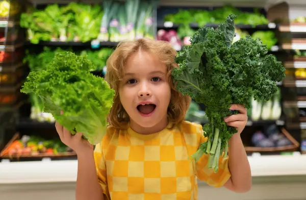 stock image Child with lettuce chard vegetables. Healthy food for kids. Portrait of smiling little child with shopping bag at grocery store or supermarket. Child choosing fruit during shopping at vegetable