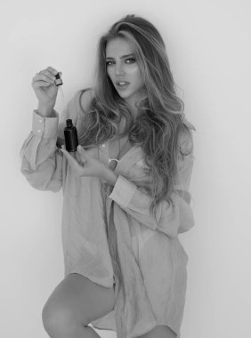 Kozmetik ve serum ürünleri. Cilt bakım ürünleri, güzellik ürünleri ve kozmetik ürünleri olan bir kadın. Kozmetik şişeli reklamcı kız, spa pazarlaması. Güzellik konsepti. Doğal cilt bakım ürünleri