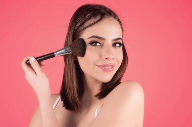 Beautiful woman applying make-up powder on the cheek. Cosmetic powder brush. Perfect skin and natural makeup