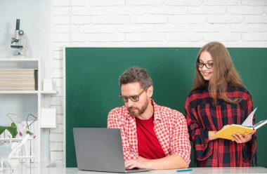 Öğretmen okul çocuğuna dersi açıklıyor. İlkokul öğrencileri öğreniyor. Bilgisayar kullanan okul çocuğu