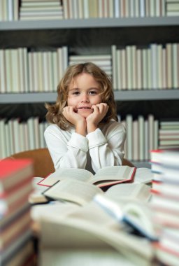 Çocuk kütüphanede kitap okuyor. Okul kütüphanesinde kitabı olan bir öğrenci. Çocuk edebiyatı. Kitaplardan öğreniyorum. Okul eğitimi ve zeki yetenekli öğrenci dehası.