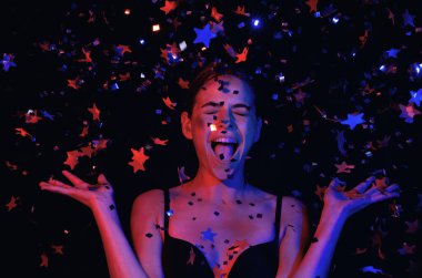 Doğum günün kutlu olsun. Konfeti üfleyen kızın stüdyo portresi. Doğum gününde ya da sevgilisinde konfeti olan güzel kız. Seksi model doğum gününde konfeti üflüyor. Doğum günü esprilerini kutlayan şehvetli kadın.