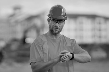 Kasklı inşaat işçisi dışarıda çalışıyor. İnşaatta sağlam bir şapkayla çalışan bir inşaatçı. İnşaat işçisi, inşaat malzemeleri. İnşaat alanında kasklı bir adam var.