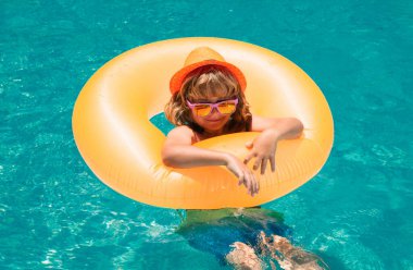 Yüzme havuzundaki çocuk şişme halkada. Çocuk turuncu şamandırayla yüzüyor. Su oyuncağı, çocuklar için sağlıklı açık hava sporları. Çocuklar plaj eğlencesi