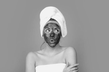 Facial treatment. Beautiful young woman with charcoal facial mask on face. Skin care and treatment. Facial black clay mask