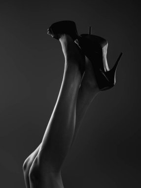 Legs of young sexy sensual slim woman in high heeled shoes on studio background. Womens legs with heels shoes. Trendy fashion high heeled shoes. Summer look with high heels. Classic high heels