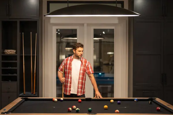 The billiard. Guy Playing billiards. Man hit ball in billiard in Billiard room. Russian pool billiards. Snooker Player. Young professional man playing billiards in the dark billiard club