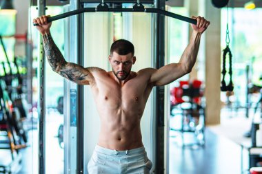 Muscular man lifting weights at gym. Handsome guy prepare to do exercises with dumbbell