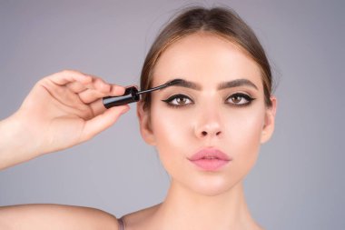 Woman comb eyebrows with eyebrow brush. Care for brows, eyebrows lamination. Brow beauty procedures. Beautiful woman with long eyelashes, eyebrows