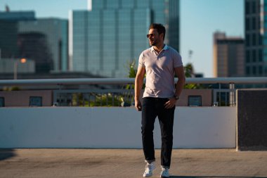 Moda mankeni, şık polo takımında şehirde yürüyor. Adam sokakta yürüyor. Şehirde yürüyen caddedeki moda adamı. Dışarıdaki şık yakışıklı adamın portresi. Çekici bir adamın portresi