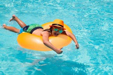 Yaz eğlencesi çocuk suratı. Çocuklar yüzme havuzunda su sıçratıyor. Çocukla yaz tatilinde su sporu aktivitesi. Çocuk oyuncakları, yüzen yüzük