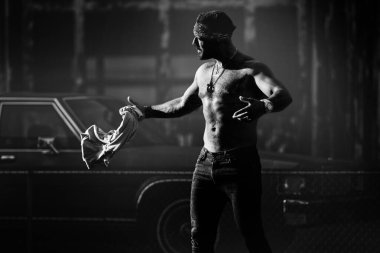 Sokaktaki gangsterler. Şehir sokağında arabanın yanında poz veren kızgın bir adam. Tehlikeli agresif adam. Suç şehri. Tehlikeli Amerikan bölgesi. Agresif ve sinirli bir adam. Ciddi adam, hipster acımasız görünüyor. Olgun adam.