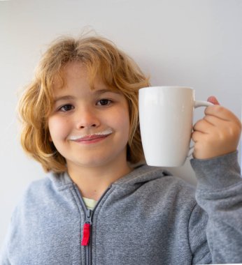 Kid holding a glass of fresh milk. Child with milk moustache drinking milk. Healthy breakfast for children. Healthy eating concept for kids. Little kid boy hold cup of milk