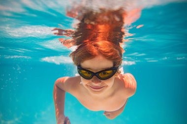 Çocuk yüzme havuzunda suya dalıyor. Küçük çocuk havuzda su altında yüzüyor. Çocuk su altında ya da havuzda yüzüyor. Yaz tatili eğlencesi. Yüzme havuzundaki su altı portresi