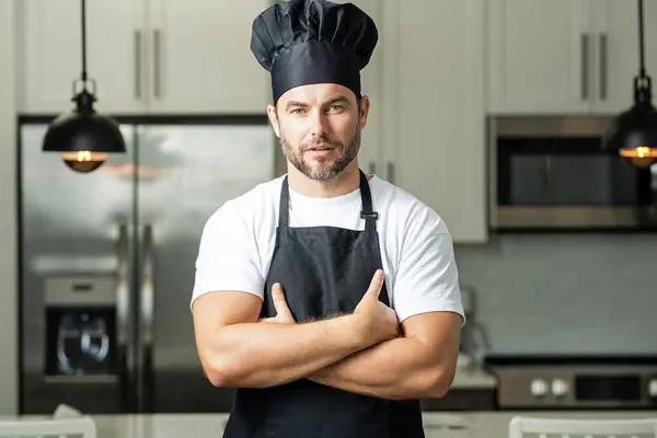 stock image Chef on kitchen. Professional chef man in uniform on kitchen. Bearded chef, cook or baker. Male chef over kitchen background. Handsome man in chefs uniform with chefs hat cooking in the kitchen