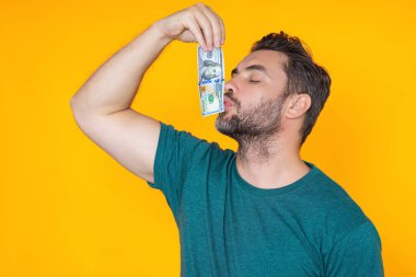 İyi ödeme. Yakışıklı adam gri stüdyoda izole edilmiş para tutuyor. Dolar banknotları halinde para. Yığınla para, finans, yatırım ve tasarruf