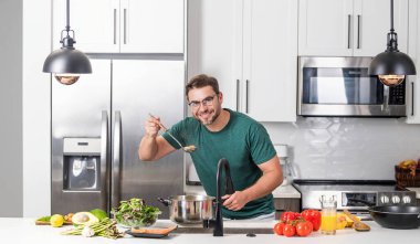 Adam mutfakta yemek pişiriyor. Aşçı şefi tencereli bir yemek hazırlıyor. Menü tarifi sağlıklı yemek. Adam modern mutfakta yemek pişiriyor. Olgun bir adam mutfakta yemek hazırlıyor.