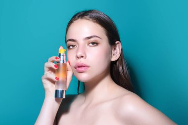 Parfüm kullanan güzel romantik bir kız. Parfüm şişesi olan kadın. Kadın parfümleri sunar. Parfüm şişesi, sprey aroma. Kadın parfüm şişesi tutuyor.