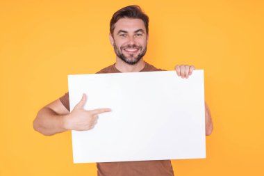 Boş afişi olan mutlu adam stüdyo arka planında izole edilmiş. Boş posteri olan çekici bir adamın portresi. Poster gösteren, tabela üzerinde parmak gösteren bir adam. Pano veya afiş konsepti