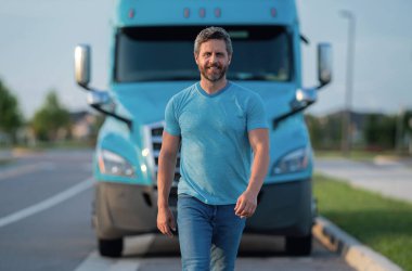 Kamyonun yanında erkek sürücü var. Kamyonun yanında bir kamyon şoförü var. Yakışıklı, orta yaşlı kamyoncu kamyoncu adam. Ulaşım endüstrisi araçları. Kamyonun önündeki yakışıklı adam.