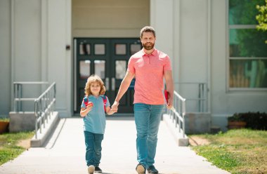 Baba oğlunu destekliyor ve motive ediyor. Çocuk ilkokula gidiyor. Okul kapısının önünde çocuklu bir ebeveyn. Babam okula çocuğuyla birlikte gidiyor.