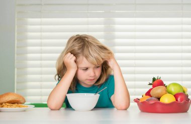 İştahsız bir çocuğun portresi. İştah kaybı kavramı. Çocuk portresi evde taze sağlıklı yiyecekler yiyor. Çocuk okuldan önce kahvaltı yapıyor.