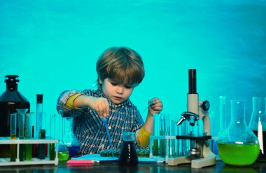 İlkokuldan bir çocuk. Test tüpüyle deney yapan mutlu küçük bilim adamı. okul çocuğu. Okul öncesi. Kimya alanında yeni bir deney yaptılar..