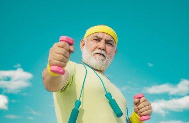 Yaşlı, olgun bir adam halterle egzersiz yapıyor. Sağlıklı yaşam tarzı kavramı. Dedem halterle egzersiz yapıyor. Son sınıf öğrencileri için spor