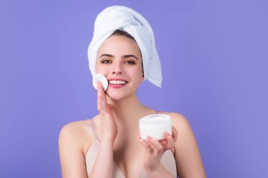 Removing makeup with cotton pads. Cleaning face with pad. Cosmetic cotton pad. Young woman caring for facial skin using cotton pad in studio. Beauty care and pampering. Daily skincare