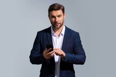 Cep telefonu kullanan takım elbiseli yakışıklı bir iş adamı, izole edilmiş bir stüdyo geçmişi var. Cep telefonu kullanan orta yaşlı İspanyol işadamının portresi. Akıllı telefonu olan adam stüdyo geçmişini izole etmiş.