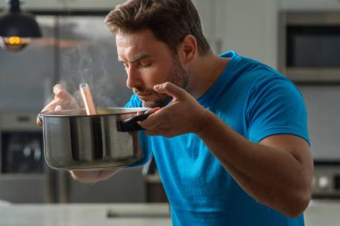 Aşçı mutfakta yemek pişiriyor. Şef aşçı tencereli bir yemek hazırlıyor. Menü tarifi sağlıklı yemek. Şef modern mutfakta yemek pişiriyor. Olgun aşçı mutfakta yemek hazırlıyor.