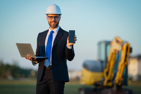 Builder engineer or civil engineer worker at a construction site. Engineer worker in suit and helmet at construction site. Supervisor construction manager near excavator. Renovation building concept