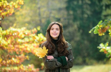 Mutlu sonbahar kadını parkta yapraklarla eğleniyor.