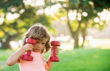 Çocuklar sportif yaşam tarzı aktiviteleri. Çocuk parkta dambılla antrenman yapıyor. Çocuk sporu. Çocuk dışarıda egzersiz yapıyor.