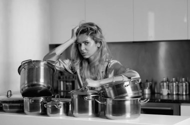 Tered ev hanımı mutfakta yemek pişiriyor. Ev hayatı işte. Sıkıcı kadın sabah mutfakta yemek hazırladı. Tencere dibin kara