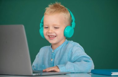 Dizüstü bilgisayar kullanan şirin bir çocuk, online e-öğrenme yoluyla okuyan bir çocuk. Küçük komik sistem yöneticisi.