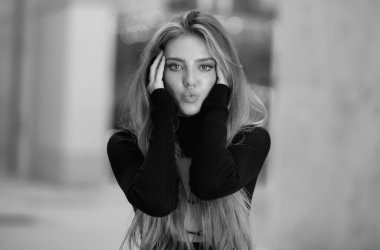 Mutlu, gülümseyen, hava öpücüğü veren, olumlu duyguları olan bir kadın. Şehvetli bir kadın, moda mankeni, sokak ortasında poz veren günlük kıyafetler. Stil kızı yaz koleksiyonu