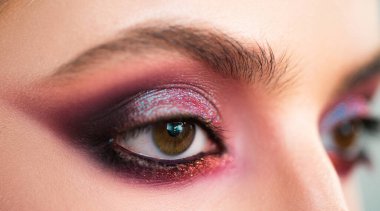 Mor dumanlı göz makyajı. Yakın çekim fotoğrafı. Profesyonel dumanlı gözler, özel durumlar için güzel bir kıza makyaj yapar. Göz makyajındaki parlak pigmentler. Lüks göz makyajı konsepti