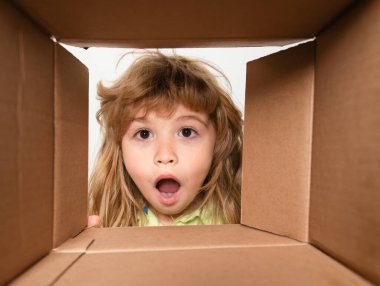Hediye kutusunu karıştıran, komik bir ifadeyle hediye paketini açan sabırsız çocuk boks sürprizi. Paketleme ya da boşaltma konsepti. Yakın çekim çocuk yüzü.