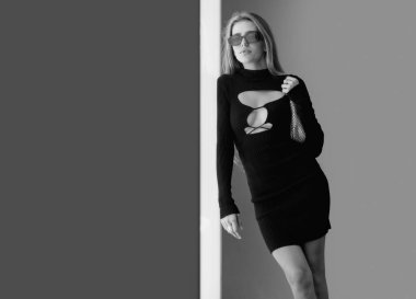 Moda kıyafetleri içinde genç ve güzel bir kadın. Açık havada siyah elbiseli bir manken.