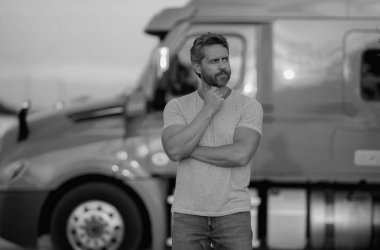 Kamyonun yanında erkek sürücü var. Kamyonun yanında bir kamyon şoförü var. Yakışıklı, orta yaşlı kamyoncu kamyoncu adam. Ulaşım endüstrisi araçları. Kamyonun önündeki yakışıklı adam.