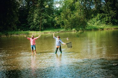 Takım elbiseli kıdemli balıkçı ve balıkçı oltasıyla balıkçılık yapan sıradan bir adam.